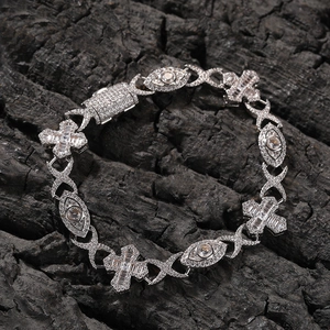 Detailed view of hip hop cross bracelet with white zircons on dark textured surface