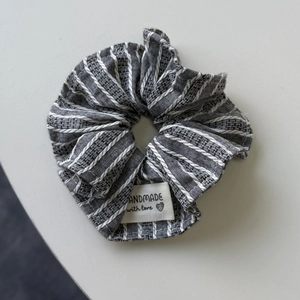 Gros plan sur chouchou en tissu à rayures grises avec texture tissée et étiquette