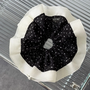 Close-up of oversized black and white polka dot scrunchie with ruffled trim and chiffon texture