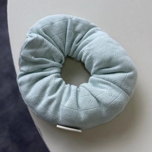 Close-up of mint green pointelle knit fabric texture and ruffles on a large scrunchie