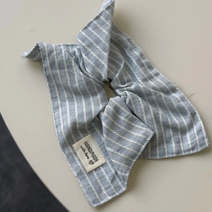 Détail d'un chouchou en tissu rayé bleu avec étiquette fait main sur fond gris