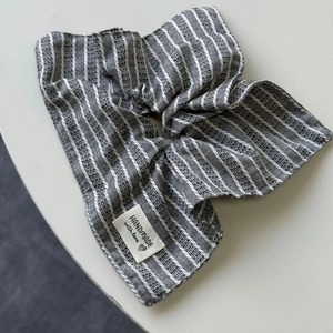 Détail d'un chouchou en tissu à rayures gris et blanc avec étiquette fait main