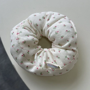 Detail of floral pointelle knit fabric on an off-white oversized scrunchie with tag