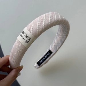 Détail d'un bandeau rayé rose avec une étiquette en tissu faite à la main et texte