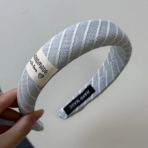 Détail du chouchou rayé bleu clair avec étiquettes tissées main et texture en coton
