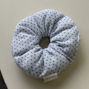 Close-up of light blue polka dot scrunchie featuring detailed fabric texture and floral label