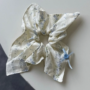 Detail of floral bow scrunchie with lace edge, blue flower pattern and button decor