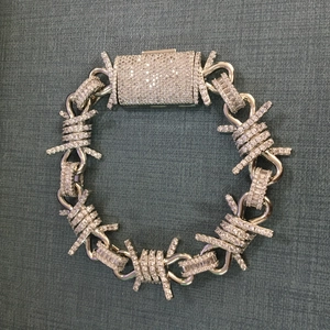 Macro view of iced out silver barbed wire necklace with diamond paved clasp