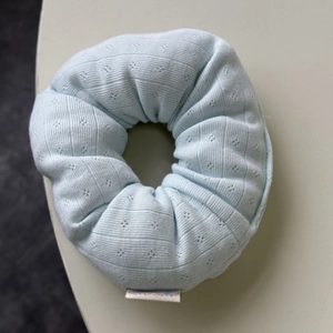 Detail view of light blue ribbed knit scrunchie with floral tag and textured diamond pattern