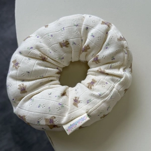 Detailed view of beige knit scrunchie with brown bear and purple floral prints