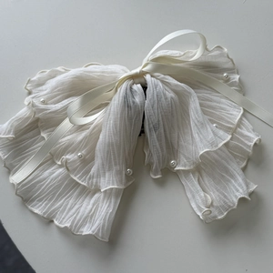 Détail macro d'une grande pince à cheveux en tulle plissé blanc avec perles et rubans