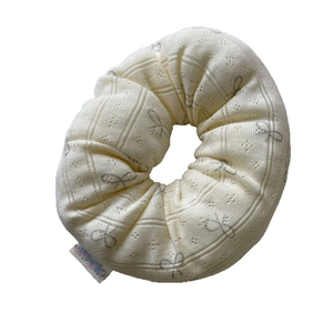 Creamy white pointelle knit scrunchie with dark grey bow print and stitched label