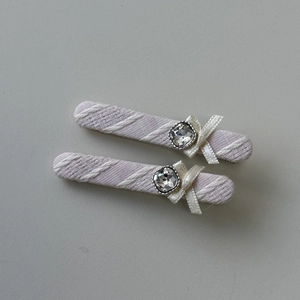 Détail de barrettes à rayures lilas avec des nœuds en satin et des accents cristallins