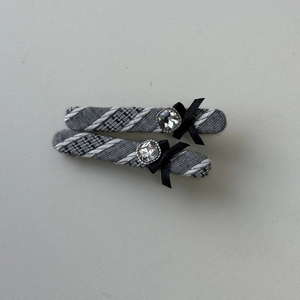 Détail de barrettes à carreaux gris avec nœuds en ruban noir et strass étincelants