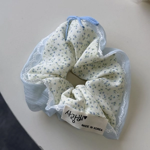 Macro-opname van een bloemen scrunchie met blauwe stof, kant en een stoffen label