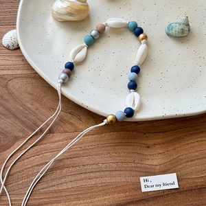 Vue détaillée du collier artisanal en coquillages et perles colorées sur un plateau