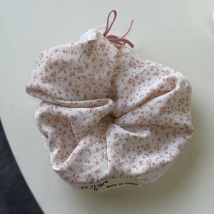 Detail van roze gebloemde scrunchie met witte kant en Koreaans tekstlabel
