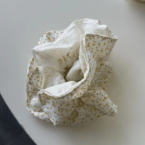 Detailopname van pluizige bloemen scrunchie met geel bloemenpatroon op beige stof