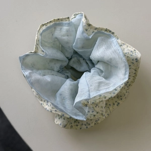 Detail van een gebloemde scrunchie met lichtblauwe chiffon en madeliefjespatroon stof