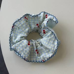 Detail of blue gingham scrunchie with cherry prints and scalloped navy edge stitching