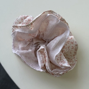Detail van een bloemen scrunchie met roze bloemmotieven op crème chiffon stof