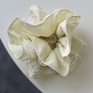 Vue détaillée du chouchou en dentelle beige avec broderie fine et texture de tissu doux