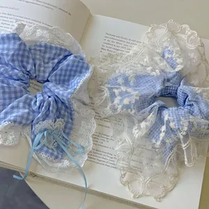 Light blue plaid scrunchie set with white lace trim and ribbon on a vintage book