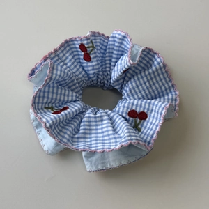 Macro detail of striped scrunchie featuring red cherry embroidery and pink wavy edges