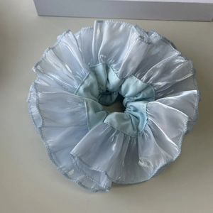 Detail der Lagen aus hellblauem, durchsichtigem, plissiertem Stoff auf dem Scrunchie