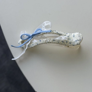 Detail van de gele bloemen haarklem met witte kantafwerking en een blauwe strik