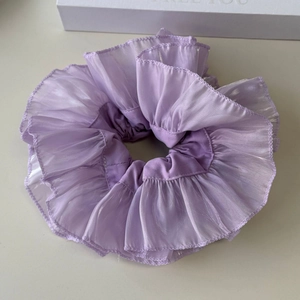 Detail eines lavendelfarbenen Organza-Scrunchies mit Rüschen und schimmerndem Glanz