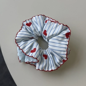 Detail of blue striped scrunchie with red scalloped edges and embroidered hearts