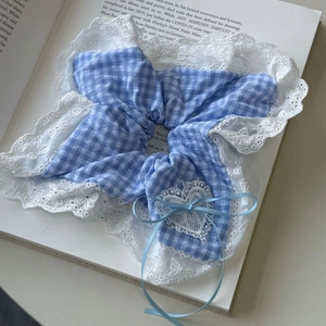 Close-up of blue plaid scrunchie with floral lace edges and a delicate ribbon bow