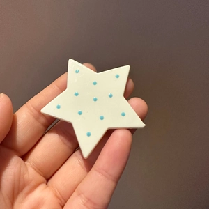 Close-up of star-shaped hair clip with blue polka dots on a white resin finish