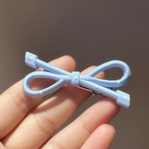 Macro detail of sky blue bow hair clip with white polka dots and silver metal clip