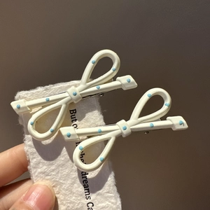 Detailed view of cream bow hair clips with blue polka dots on a vintage card
