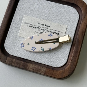 Dettaglio del fermaglio per capelli floreale con bacche blu e clip in metallo dorato