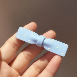 Detail of light blue polka dot bow hair clip with glossy resin finish for girls