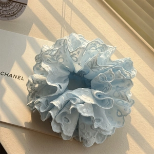 Détail d'un chouchou en dentelle bleu clair avec broderie et texture de nuage