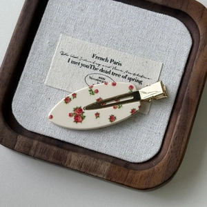 Dettaglio del fermaglio per capelli vintage a fiori su un vassoio di legno