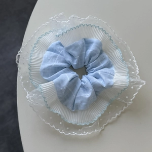 Détail d'un chouchou en tissu bleu à carreaux avec dentelle blanche et tulle