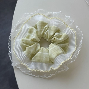 Détail d'un chouchou à plusieurs épaisseurs avec dentelle jaune et tissu à carreaux verts