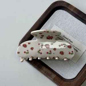 Dettaglio della molletta per capelli crema con rose rosse e strass scintillanti