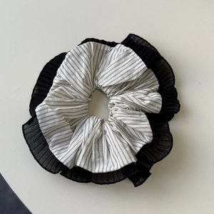 Detail of layered hair scrunchie featuring grey stripes and black pleated gauze edges