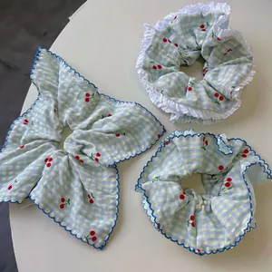 Detail of blue plaid hair scrunchie set with cherry print and white ruffle lace edges