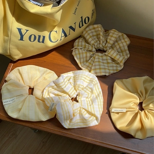 Set aus vier gelben koreanischen Satin- und Karomuster-Scrunchies auf Holztisch