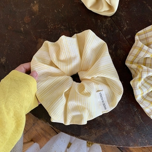 Übergroßes gelbes Karo-Haargummi mit Spitze über einem dunklen Vintage-Holzhintergrund