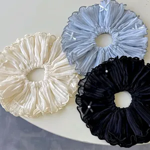 Elegant oversized satin scrunchies with bow ribbons and pearls in beige, blue, and black