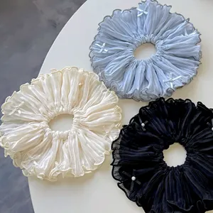 Three pleated oversized scrunchies in blue, beige, and black with pearls and bows