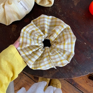 Detail eines übergroßen gelben Karo-Haargummis mit weicher Satintextur für das Styling